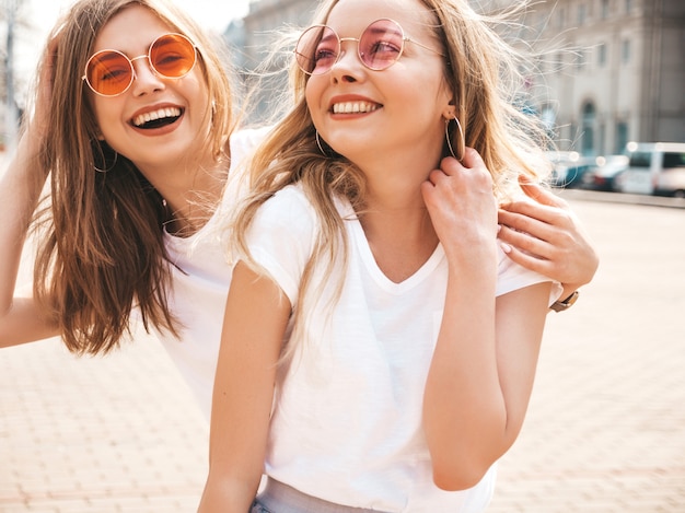 Portret van twee jonge mooie blonde glimlachende hipster meisjes in kleren van de trendy de zomer witte t-shirt.