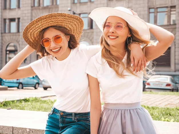 Portret van twee jonge mooie blonde glimlachende hipster meisjes in kleren van de trendy de zomer witte t-shirt.