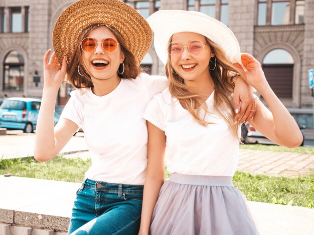 Portret van twee jonge mooie blonde glimlachende hipster meisjes in kleren van de trendy de zomer witte t-shirt.