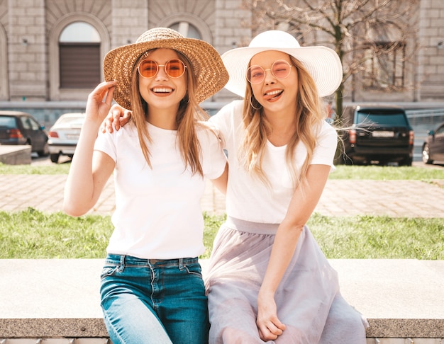 Portret van twee jonge mooie blonde glimlachende hipster meisjes in kleren van de trendy de zomer witte t-shirt.