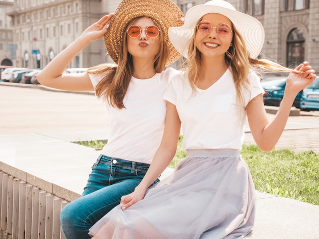 Portret van twee jonge mooie blonde glimlachende hipster meisjes in kleren van de trendy de zomer witte t-shirt.