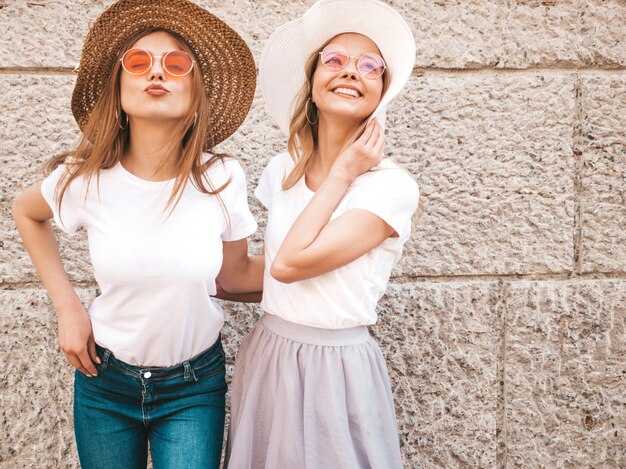 Portret van twee jonge mooie blonde glimlachende hipster meisjes in kleren van de trendy de zomer witte t-shirt.