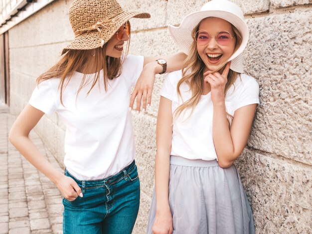 Portret van twee jonge mooie blonde glimlachende hipster meisjes in kleren van de trendy de zomer witte t-shirt.