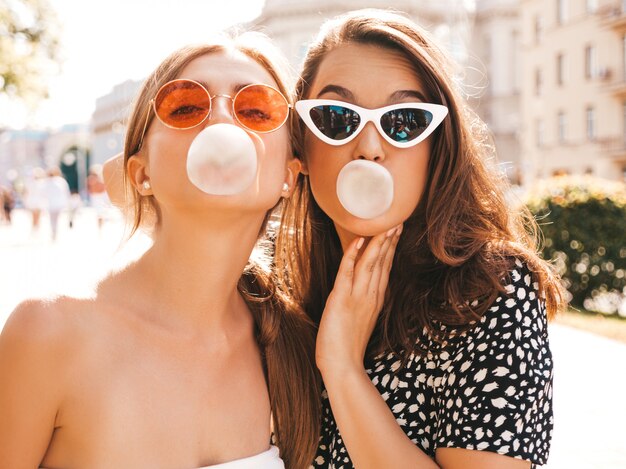 Portret van twee jonge mooie glimlachende hipster meisjes in trendy zomerkleren