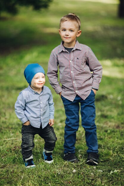 Portret van twee kleine jongens die een casual uiterlijk dragen en poseren in het park, hand in hand in de zakken Knappe broers die samen wandelen en spelen Concept van modieuze en stijlvolle kinderlook van kleding