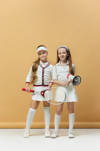 Portret van twee meisjes als tennisspelers die tennisracket houden.