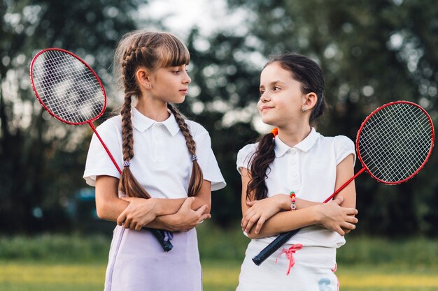 Portret van twee meisjes die badminton houden die elkaar bekijken