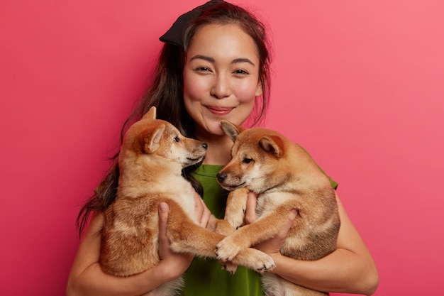 Portret van twee schattige lieve puppy's die familieleden zijn, poseren op de handen van de vrouw, met elkaar spelen, zich voorbereiden op de wandeling.