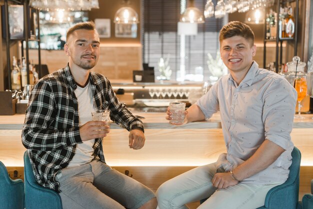 Portret van twee vrienden die met drank in bar vieren