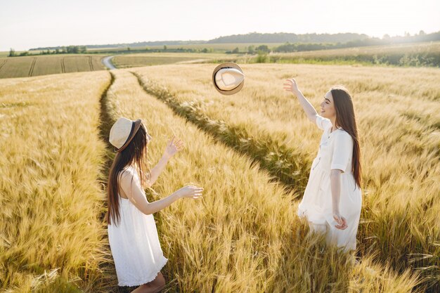 Portret van twee zussen in witte jurken met lang haar in een veld