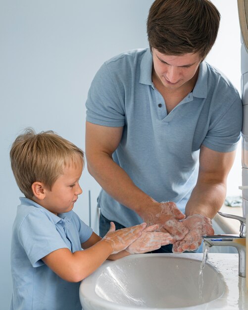 Portret van vader die zoon leert hoe om handen te wassen