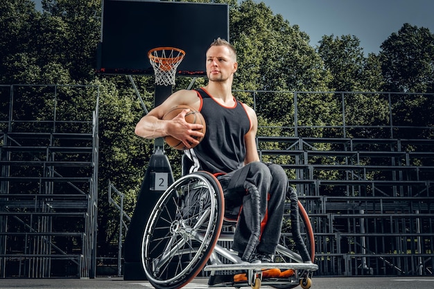 Gratis foto portret van verlamde basketbalspeler in rolstoel op open speelterrein.