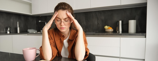 Portret van vermoeide jonge werkende vrouw in bril houdt handen op het hoofd lijdt aan pijnlijke migraine heeft