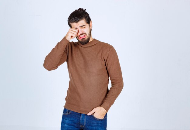 Portret van vermoeide man met haren wrijven ogen tegen grijs witte achtergrond. . Hoge kwaliteit foto