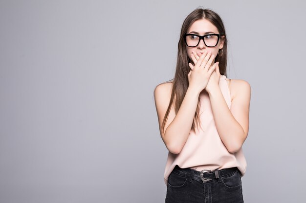 Portret van verrast mooie vrouw die haar hoofd in verbazing en met open mond op de witte muur