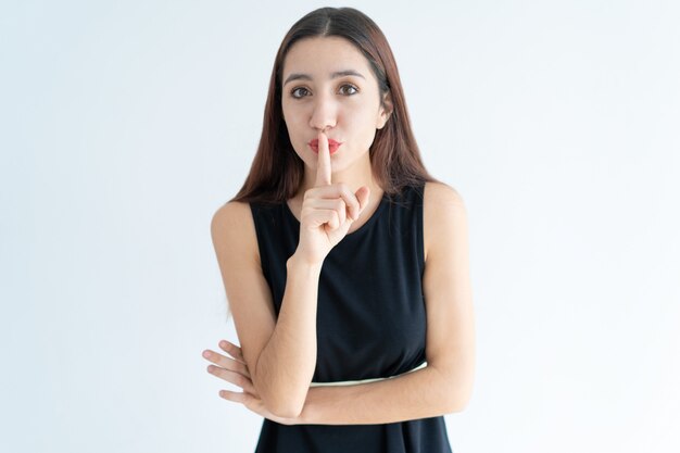 Portret van vertrouwen jonge vrouw met vinger op de lippen