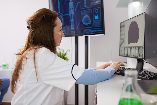 Portret van volwassen bioloog vrouw die op de computer werkt. moderne apparatuur in een microbiologisch laboratorium.