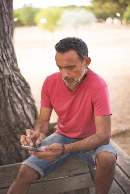 Gratis foto portret van volwassen man die smartphone buitenshuis gebruikt