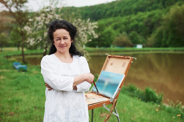 Portret van volwassen schilder met zwart krullend haar in het park buiten