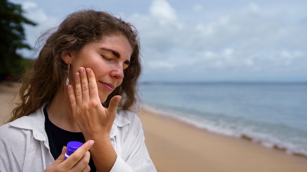 Gratis foto portret van volwassen vrouw die lotion op zonnebrandhuid toepast