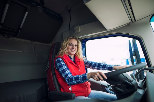 Portret van vrachtwagenchauffeur zittend in de vrachtwagencabine met de handen op het stuur