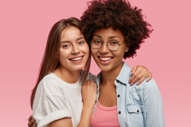 Portret van vriendelijke multi-etnische vrouwen glimlachen breed, knuffelen en genieten van saamhorigheid, poseren voor familieportret