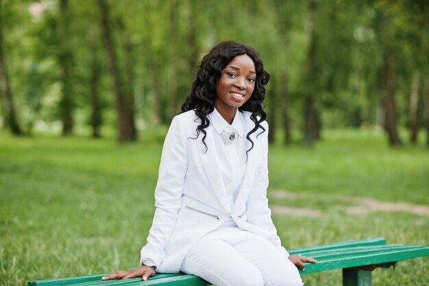 Portret van vrij zwarte afrikaanse amerikaanse meisjeszitting op bank bij groen park