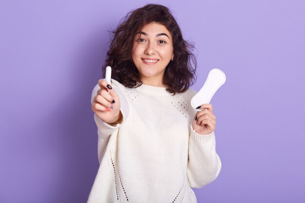 Portret van vrolijke aantrekkelijke jonge dame met tampon en maandverband