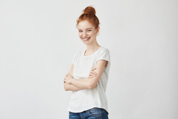 Portret van vrolijke jonge roodharige vrouw lachen met gekruiste armen.