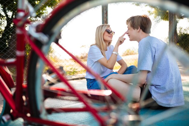 Portret van vrolijke jongen en meisje in zonnebril zittend op de vloer en gelukkig samen spelen Jonge mooie paar plezier terwijl ze tijd doorbrengen in het park