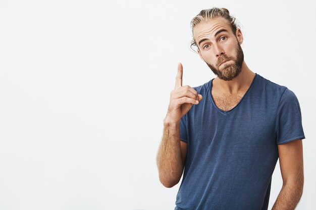 Portret van vrolijke mooie mannen met modieuze kapsel en baard, die omhoog wijst