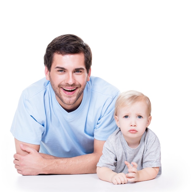 Portret van vrolijke vader met kleine baby liggend op de vloer - geïsoleerd op wit