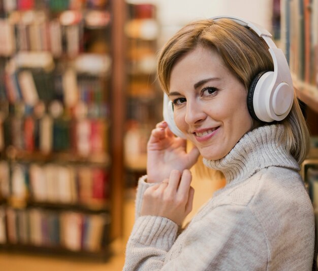 Portret van vrouw die hoofdtelefoons op hoofd in boekhandel draagt