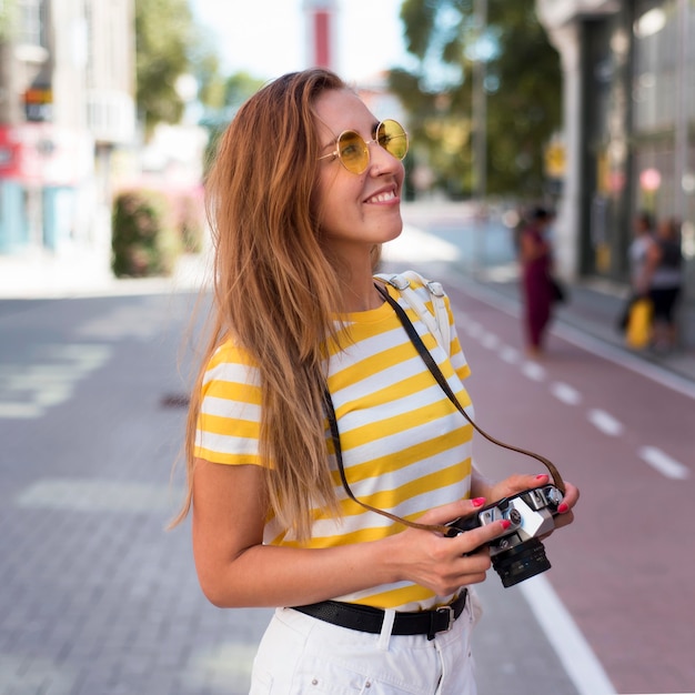 Gratis foto portret van vrouw met camera in stad