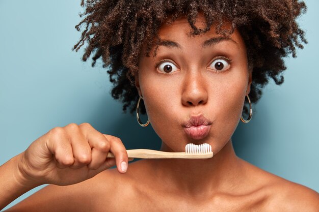 Portret van vrouw met de tandenborstel van de Afro-kapselholding