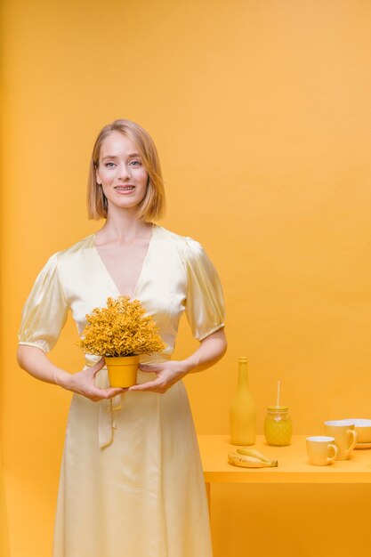 Portret van vrouw met een bloempot in een gele scène