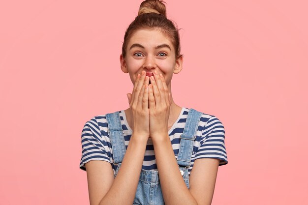 Portret van vrouw met haar in een broodje en het dragen van denimoveralls