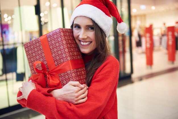 Portret van vrouw met kerstcadeautje in de winkel