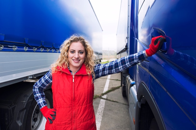 Gratis foto portret van vrouw vrachtwagenchauffeur permanent door vrachtwagen voertuig