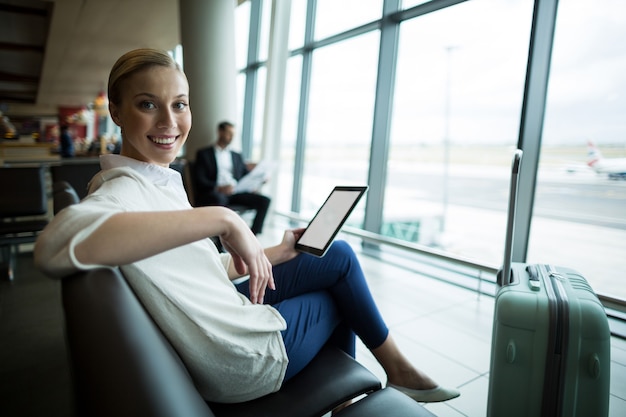 Portret van vrouwelijke forens met digitale tabletzitting in wachtruimte