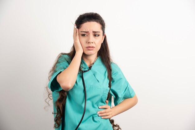 Portret van vrouwelijke gezondheidswerker die haar hoofd aanraakt.