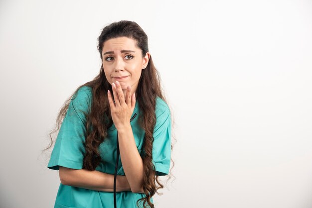 Portret van vrouwelijke gezondheidswerker die zich voordeed op witte muur.