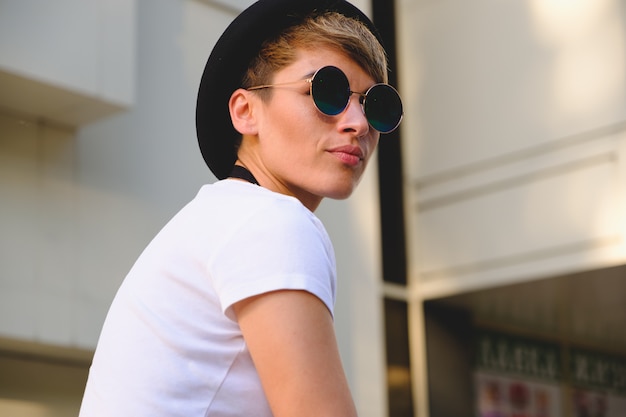 Portret van vrouwelijke hipster met natuurlijke make-up en kort kapsel die in openlucht van vrije tijd genieten