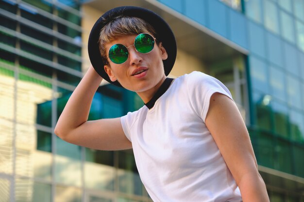 Portret van vrouwelijke hipster met natuurlijke make-up en kort kapsel die in openlucht van vrije tijd genieten