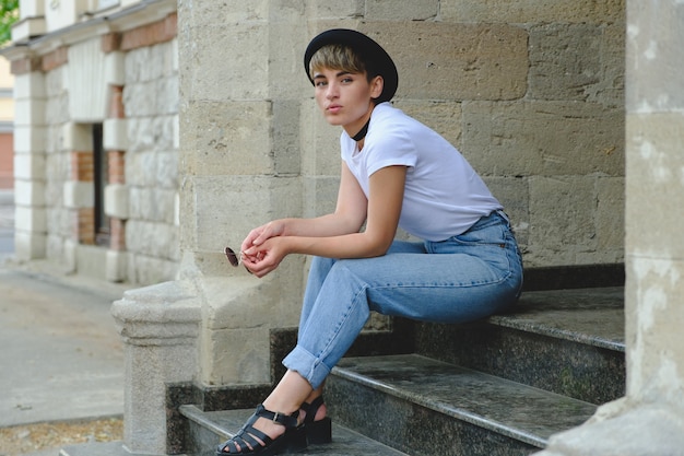 Portret van vrouwelijke hipster met natuurlijke make-up en kort kapsel die in openlucht van vrije tijd genieten