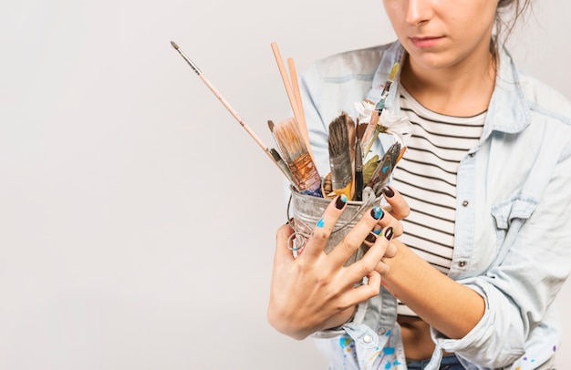 Gratis foto portret van vrouwelijke kunstenaar met penselen