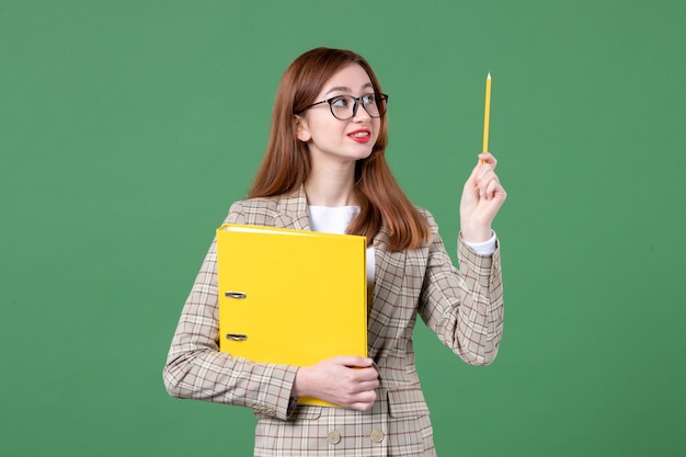 Portret van vrouwelijke leraar met gele bestanden op groen