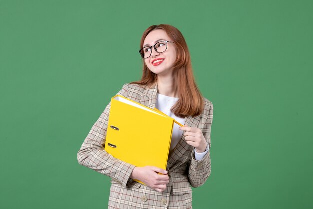 Portret van vrouwelijke leraar met gele bestanden op groen