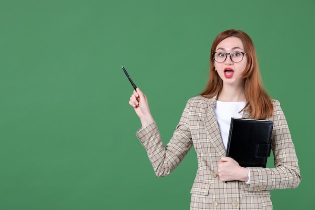 Portret van vrouwelijke leraar met notitieblok op groen