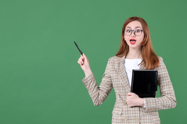 Portret van vrouwelijke leraar met notitieblok op groen